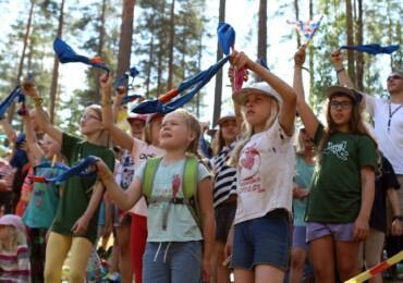 Lapsia heiluttaa partiohuiveja tapahtuman yleisössä