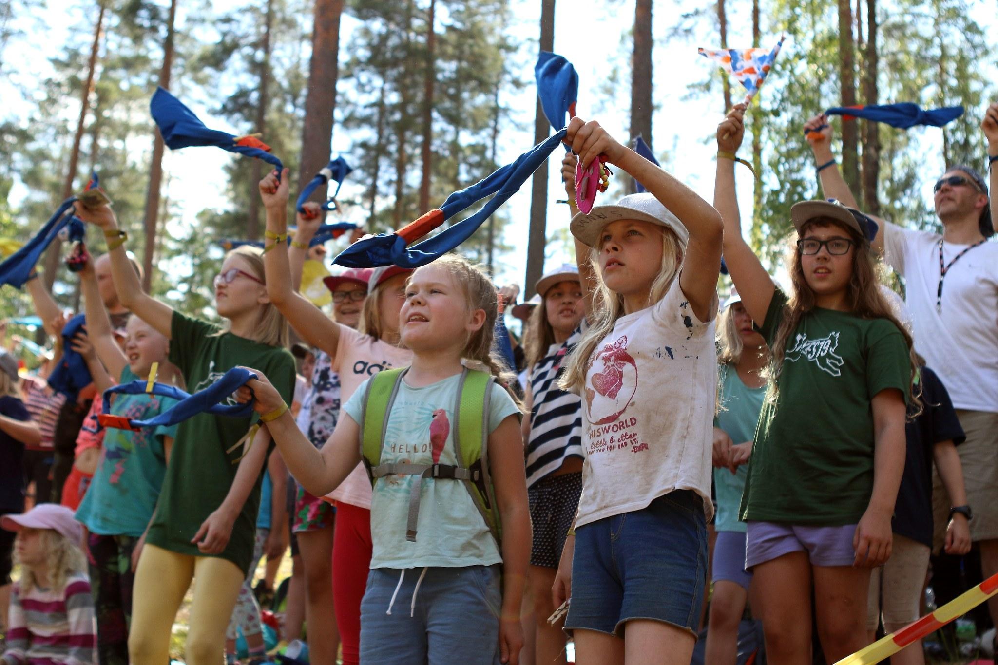 Lapsia heiluttaa partiohuiveja tapahtuman yleisössä